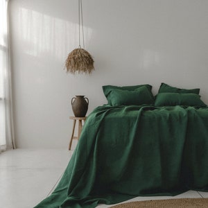 Könnte beinhalten: Ein grünes Bettwäsche-Set aus Leinen in einem tiefen Grünton. Die Bettwäsche liegt auf einem Bett mit einem Holz-Beistelltisch und einer Vase. Die Bettwäsche ist aus 100% Leinen gefertigt und weich und bequem.