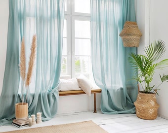 May include: A window with light blue sheer curtains, a wooden bench with a white cushion, a potted plant with a woven basket, and a woven lampshade hanging from the ceiling.