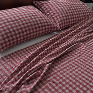 May include: A bedding set featuring a red and white gingham check pattern. The set includes two rectangular pillows and a flat sheet draped over a bed. The fabric displays a consistent grid design with a soft, matte texture across all pieces.