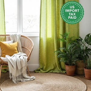 Puede incluir: Un salón luminoso con cortinas verde lima y una silla de mimbre con cojines y una manta con flecos. Una alfombra redonda de yute y plantas en macetas crean un ambiente cálido. La habitación está llena de luz natural.