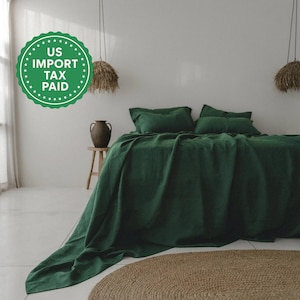 Könnte beinhalten: Ein Bett mit dunkelgrüner Bettwäsche, einschließlich Bettbezug und Kissen, ist der Mittelpunkt des Raumes. Ein runder, gewebter Teppich liegt am Fuß des Bettes. Der Raum hat ein minimalistisches Design mit neutralen Wänden und natürlichem Licht.