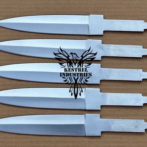 Può includere: Cinque lame di coltello argentate non rifinite, con punte affilate e codoli rettangolari, sono disposte su una superficie marrone. Le lame provengono da Kestrel Industries, come indicato dal logo al centro.