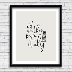 以下が含まれることがあります： 白い背景に黒い文字で「i'd rather be in italy」と書かれた黒い額縁のプリント。ピサの斜塔の白黒イラストが描かれている。