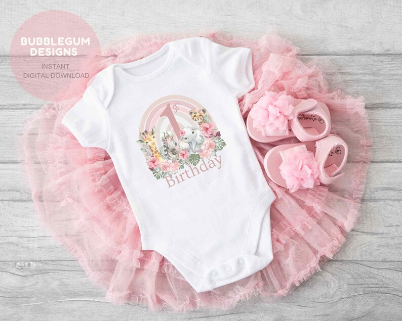 May include: White baby onesie with a pink and green jungle animal design and the text "1st Birthday".