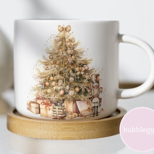 May include: White ceramic mug with a Christmas tree design. The tree is decorated with gold ornaments, bows, and a nutcracker. The mug is sitting on a wooden coaster.