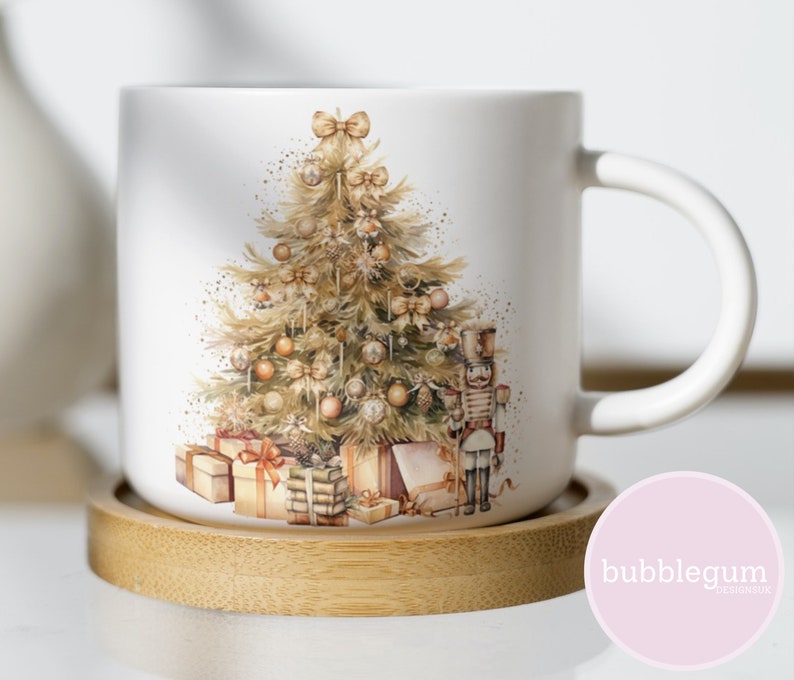 May include: White ceramic mug with a Christmas tree design. The tree is decorated with gold ornaments, bows, and a nutcracker. The mug is sitting on a wooden coaster.
