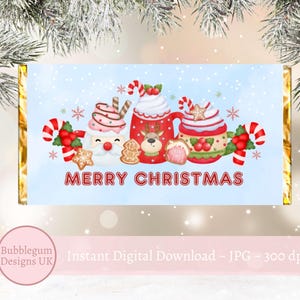 Peut inclure: Un emballage de chocolat de Noël bleu et blanc avec une canne en sucre rouge et blanche, une tasse rouge avec de la crème fouettée, un bonhomme en pain d'épices et le texte "Joyeux Noël".