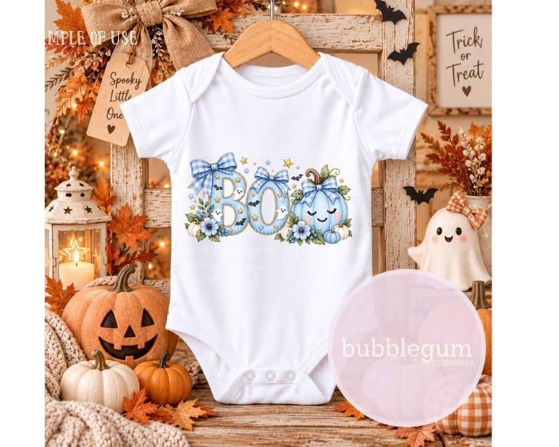 May include: A white short-sleeved baby bodysuit featuring a graphic print of the word BOO in light blue with a plaid pattern, decorated with blue bows, small ghosts, bats, stars, and a light blue pumpkin with a smiling face and floral accents.