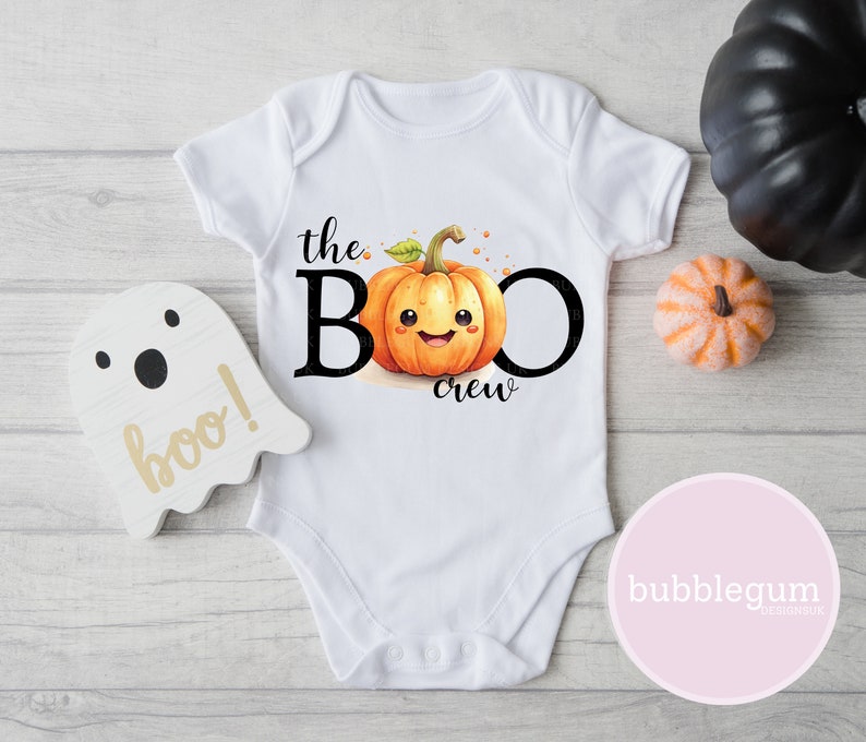 May include: White baby onesie with a cute cartoon pumpkin with a smiling face and the text "the BOO crew".