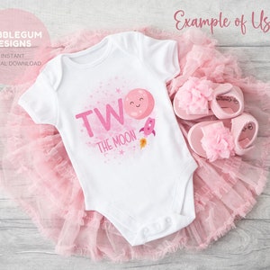 May include: A white onesie with pink lettering that says "Two the Moon" with a pink rocket and a pink moon with a smiling face. The onesie is on a pink tulle skirt.