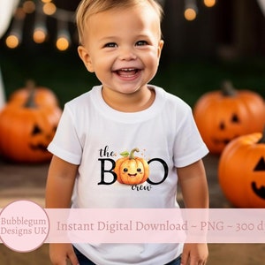 May include: A white t-shirt with the text "the BOO crew" and a smiling pumpkin graphic. The shirt is being worn by a young child in front of a background of orange pumpkins.