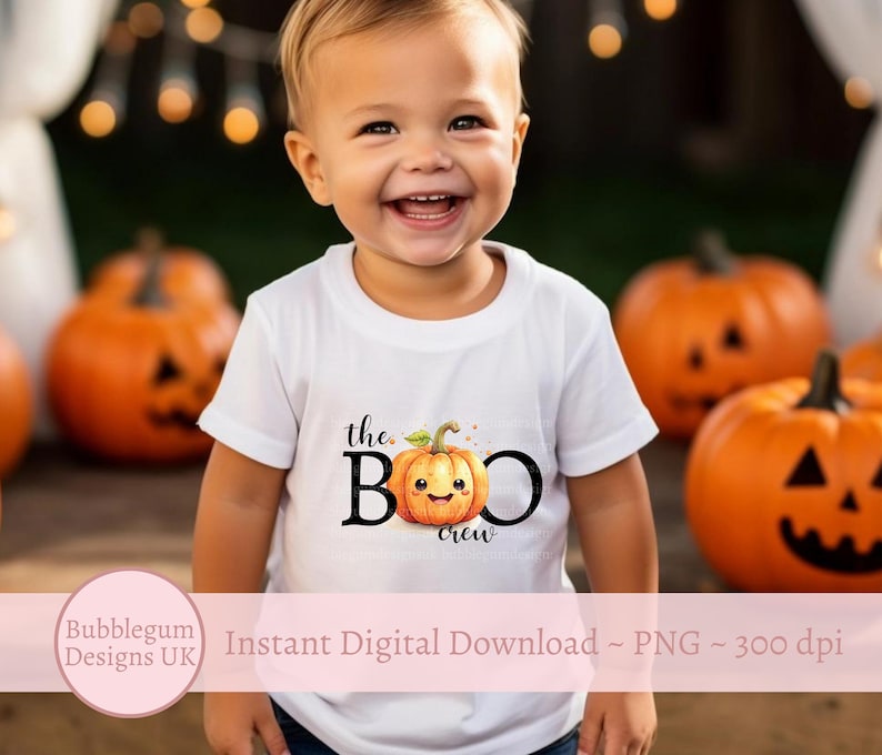 May include: A white t-shirt with the text "the BOO crew" and a smiling pumpkin graphic. The shirt is being worn by a young child in front of a background of orange pumpkins.