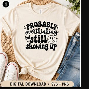 Peut inclure: Un t-shirt à manches courtes de couleur crème avec le texte noir "Probably overthinking but still showing up" et une icône de visage souriant. Le bas de l'image contient le texte "DIGITAL DOWNLOAD • SVG + PNG".