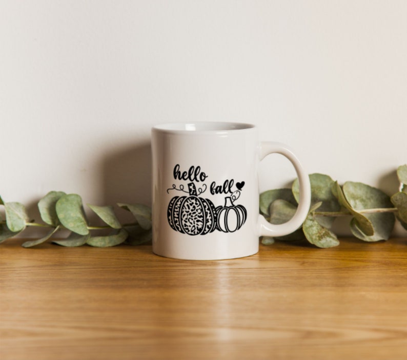 May include: White ceramic mug with a black design of two pumpkins and the text "hello fall" with a heart.