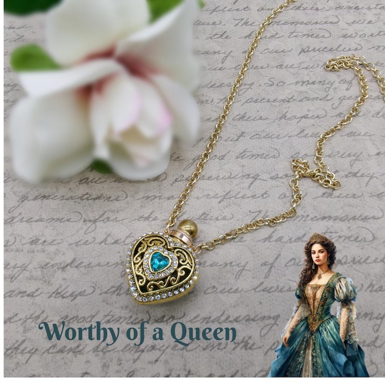 May include: Gold-tone heart-shaped pendant necklace with a blue gemstone center and clear crystal accents. The pendant is suspended from a delicate chain. The image includes the text "Worthy of a Queen".