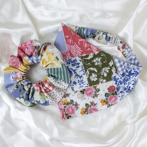 May include: A colorful patchwork scrunchie and headband set. The scrunchie and headband feature a variety of floral and patterned fabrics in shades of pink, blue, green, and yellow. The set is designed for hair accessories.
