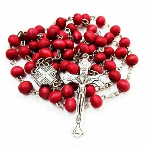 May include: A red wooden rosary with a silver crucifix and a silver charm with a cross design.