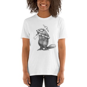 May include: White t-shirt featuring a detailed black and white illustration of a beaver wearing glasses and holding a pickaxe and a rolled-up document. The beaver is standing upright. The t-shirt is a short-sleeved style.