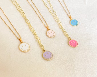 May include: Five gold chain necklaces with different colored smiley face pendants. The pendants are white, pink, purple, and blue.
