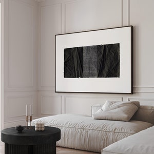 May include: A white sofa with a black and white abstract art print hanging above it. A black round coffee table with a fluted base sits in front of the sofa. The coffee table has a small black bowl and a stack of white spheres on it.