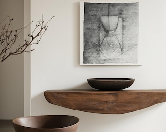Könnte beinhalten: Zwei braune Keramikschalen, eine auf einem Holzregal und eine auf dem Boden, in einem minimalistischen Interieur mit einem schwarz-weißen abstrakten Gemälde an der Wand.