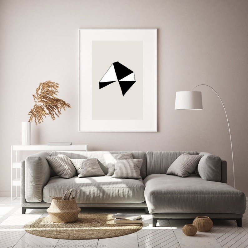 May include: A living room interior with a gray sectional sofa, a white lamp, and a framed print of a black and white geometric design on a beige background.