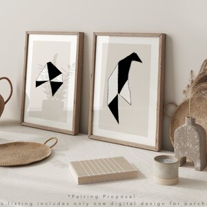 May include: Two framed abstract geometric art prints with black and white shapes on a beige background. The prints are in wooden frames and are displayed on a white surface.