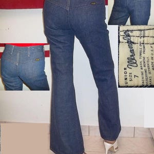 Peut inclure: Jean bleu en denim Wrangler taille junior 7, coupe &eacute;vas&eacute;e. Le jean a une taille haute et une conception classique &agrave; cinq poches. L'&eacute;tiquette est visible, et le jean est fabriqu&eacute; aux &Eacute;tats-Unis. Le mod&egrave;le porte des talons hauts blancs.