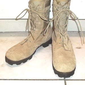 Puede incluir: Un par de botas de combate color beige. Las botas tienen un acabado similar al ante en la puntera y un material similar a la lona en la caña superior. Cuentan con un diseño con cordones y una suela de goma negra.