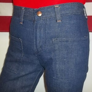 Peut inclure: Gros plan sur un pantalon en jean bleu avec deux poches avant et un bouton en cuivre. Le pantalon a une coupe droite classique et est fabriqu&eacute; dans un tissu denim durable. Les coutures sont visibles et le pantalon semble bien fait.