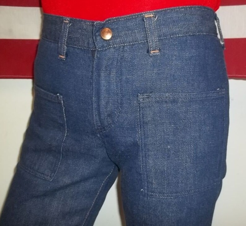 Peut inclure: Gros plan sur un pantalon en jean bleu avec deux poches avant et un bouton en cuivre. Le pantalon a une coupe droite classique et est fabriqu&eacute; dans un tissu denim durable. Les coutures sont visibles et le pantalon semble bien fait.