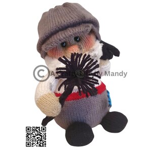 May include: A grey knitted toy with a black chimney brush, wearing a grey knitted hat and a white and red striped shirt. The toy has a black button nose and black eyes.