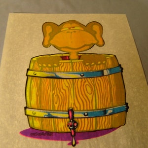 May include: A vintage iron-on patch featuring a cartoon character with large ears, sticking out of a wooden barrel with a tap. The barrel is yellow, orange, and blue. The character is yellow and orange.