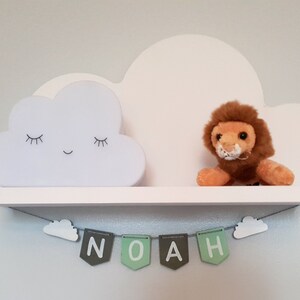 May include: White cloud shelf with a sleeping cloud nightlight, a stuffed lion, and a green and gray banner that reads "NOAH".