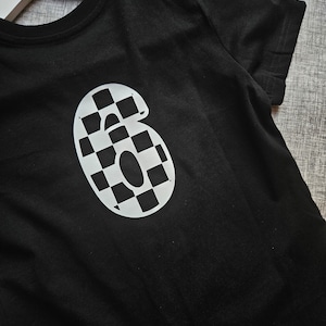 May include: Black t-shirt with a white checkered number "6" on the front.