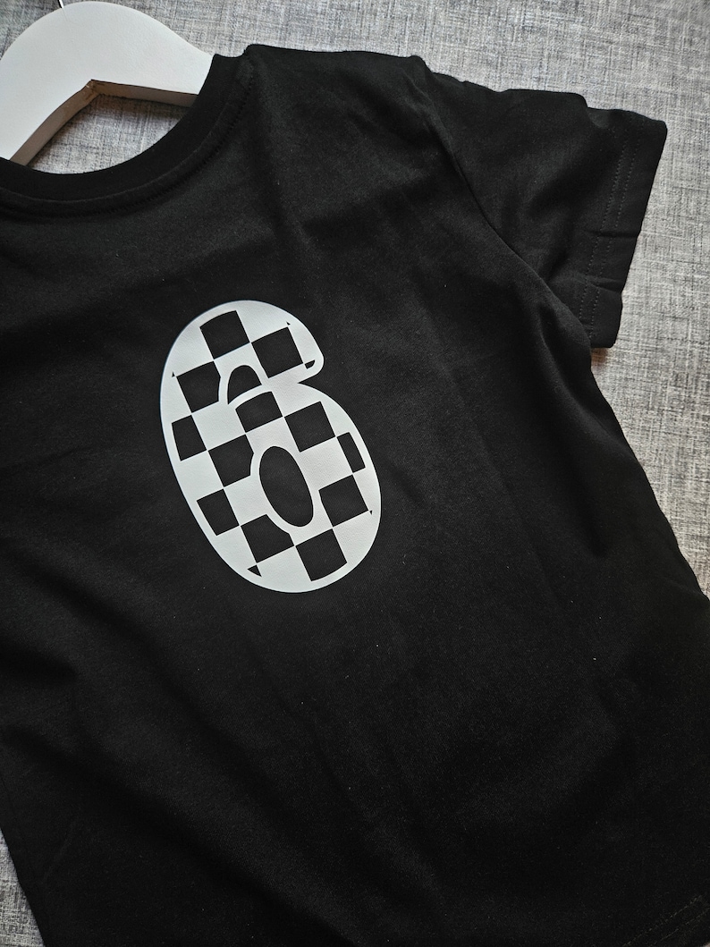 May include: Black t-shirt with a white checkered number "6" on the front.