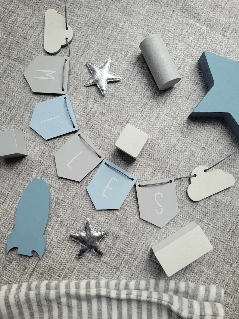 May include: A blue and gray baby mobile with a rocket, stars, clouds, and a banner that reads "MILES".