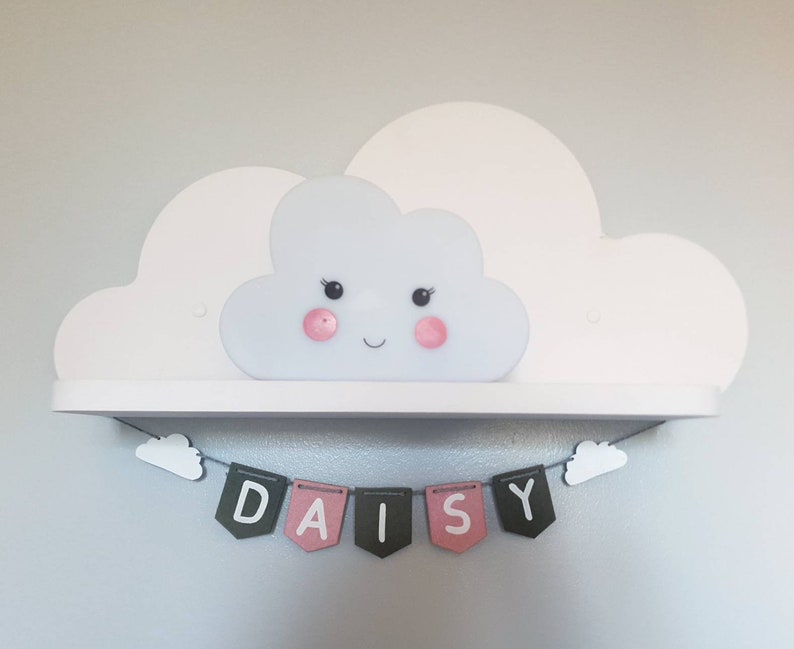 May include: A white cloud-shaped shelf with a smiling cloud-shaped light fixture. A banner with the name "DAISY" is hanging below the shelf.