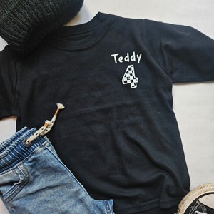 May include: Black long-sleeved t-shirt with the name "Teddy" and a chequered number "4" printed on the front.