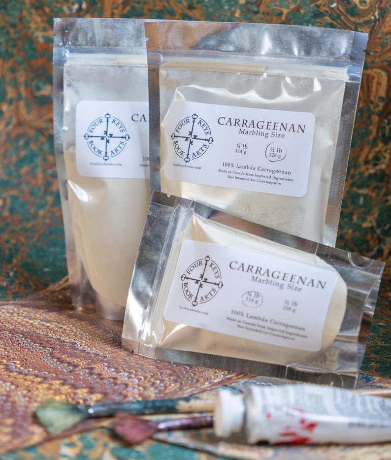 May include: Three clear plastic bags of Carrageenan marbling size, with white labels and the Four Keys Book Arts logo. The bags contain a white powder and a solid block. A tube of paint and a paintbrush are in the foreground.