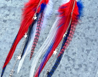 May include: A pair of patriotic feather earrings. The earrings feature red, white, and blue feathers with silver chains and star charms. The feathers are arranged in a layered design, creating a striking visual effect.