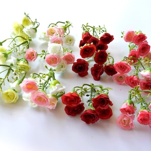 Pode incluir: Conjunto de caules de flores artificiais com pequenas flores delicadas em tons de branco, rosa, vermelho e amarelo. Cada caule apresenta várias flores agrupadas.