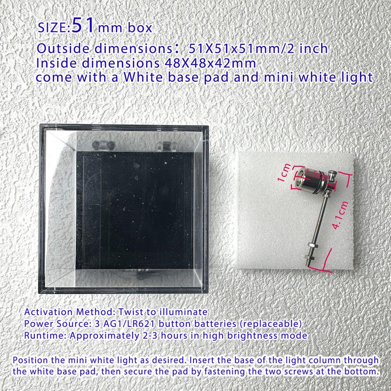 May include: A clear, square display box with a black interior, alongside a white base pad and a small light. The box measures 2 inches on each side. A small light with red and silver accents is also shown.