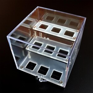 May include: A clear acrylic display case with two levels of square compartments. The case is made of clear acrylic and has a modern design.