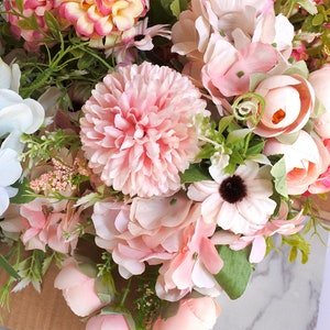 Op de afbeelding: Een boeket kunstbloemen in tinten roze, wit en perzik. Het boeket bevat hortensia's, rozen en andere bloemensoorten.