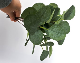 May include: A bunch of artificial eucalyptus leaves with a green color. The leaves are arranged in a bouquet and have a realistic appearance.