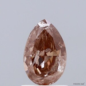 May include: A pear-shaped, faceted diamond with a warm, reddish-brown hue. The gemstone has a pointed top and a rounded base, showcasing internal reflections and a polished surface. The diamond is set against a neutral background.