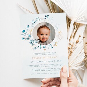 May include: Baptism invitation featuring a smiling baby's photo surrounded by a floral wreath. The invitation includes the name James Williams, date, time, and location details. The text is in a gold color.