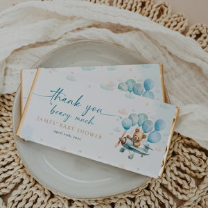 May include: A blue and white thank you card with a teddy bear in a plane holding balloons. The card says "Thank you beary much James' Baby Shower April 24th, 202x"