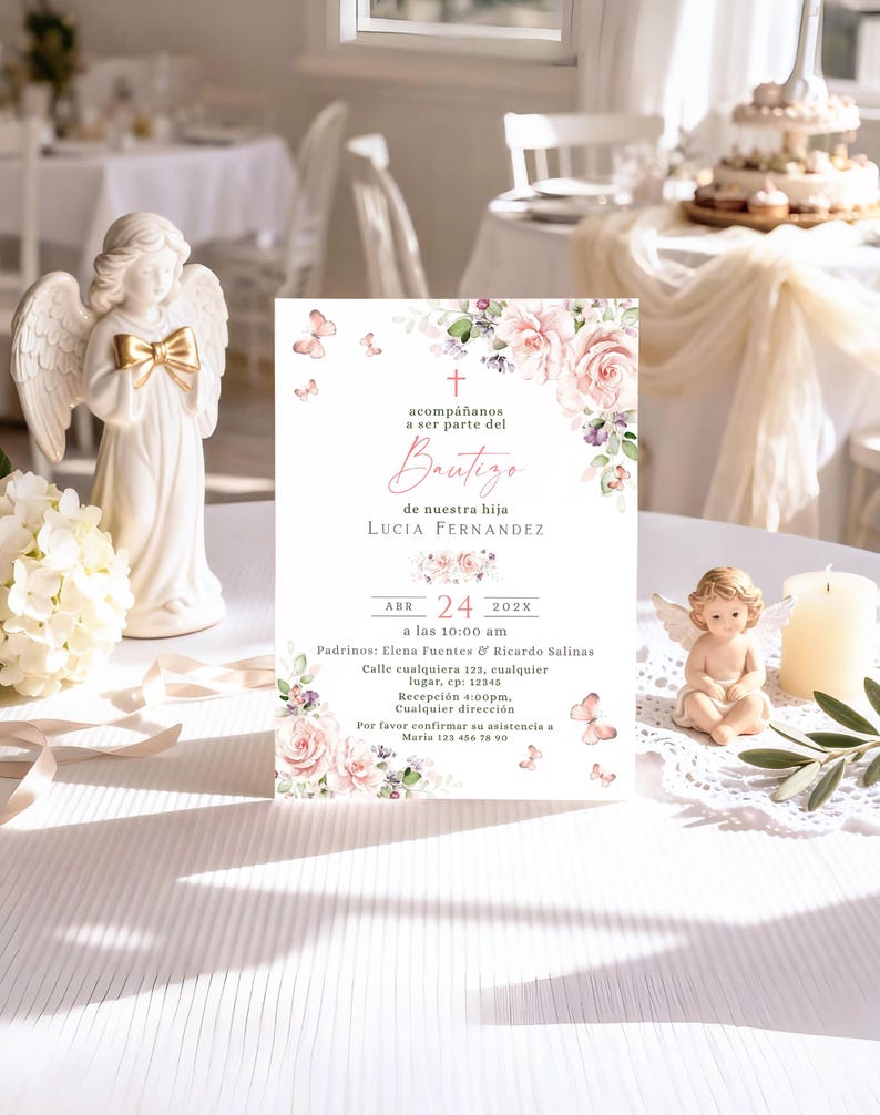 Blush rose butterfly bautizo invitation displayed upright on reception table with angel figurines, candle, and olive branch